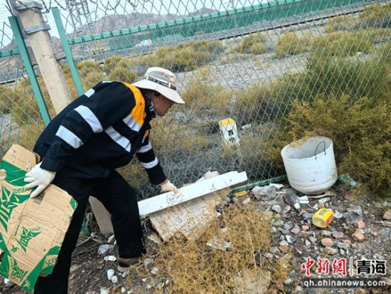 图为职工对铁路网围栏外白色垃圾进行清理。 罗维泰摄