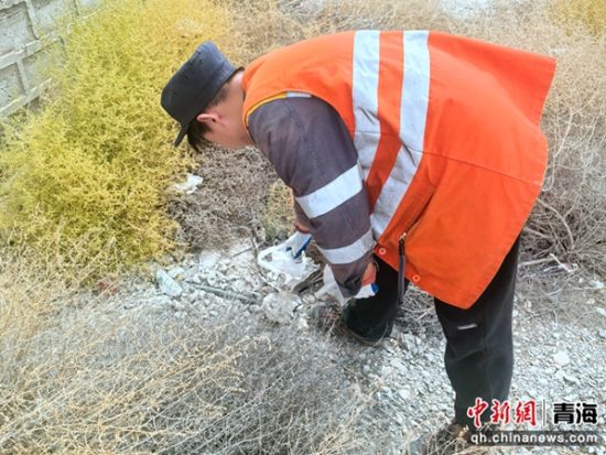 图为职工正在捡拾铁路周边轻飘浮物塑料袋。 罗维泰摄