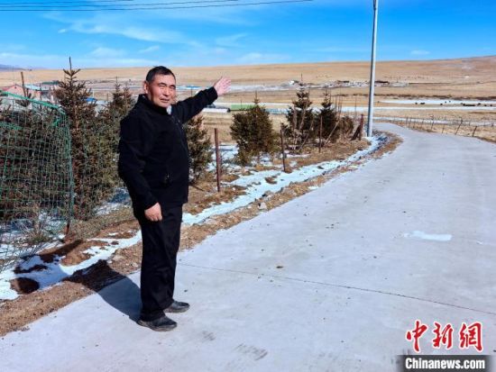 图为元才为记者介绍村里的道路情况。李隽 摄