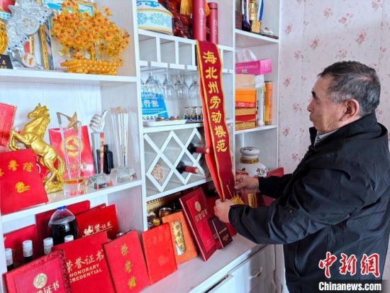 图为元才仔细整理获得的凯发真人娱乐的荣誉证书和绶带。李隽 摄