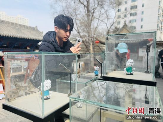 图为运动员用手机拍摄雪豹文创产品。孙睿 摄