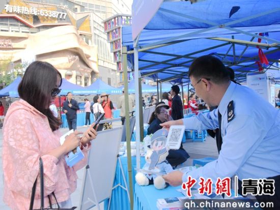 图为税务干部引导市民用手机扫描政策二维码。杜亚萍摄 图为税务干部引导市民用手机扫描政策二维码。杜亚萍摄