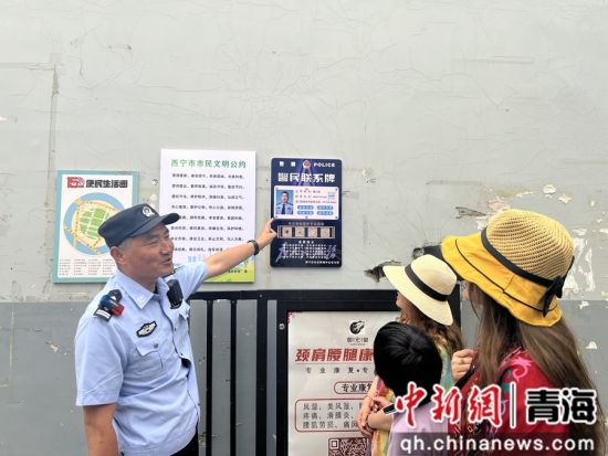 图为顾江海向游客介绍张贴的警民联系牌。赵太鑫供图 图为顾江海向游客介绍张贴的警民联系牌。赵太鑫供图