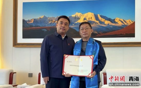 图为中共果洛州委常委、统战部部长祁乐廷(左)为阿来颁发聘书。仁增桑俄摄