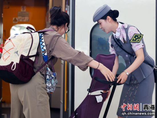 图为刘凯月在列车门口帮助旅客提拿行李。 李磊摄