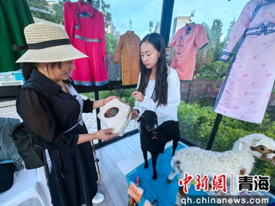 图为工作人员为游客介绍民族特色包包。李隽 摄 图为工作人员为游客介绍民族特色包包。李隽 摄