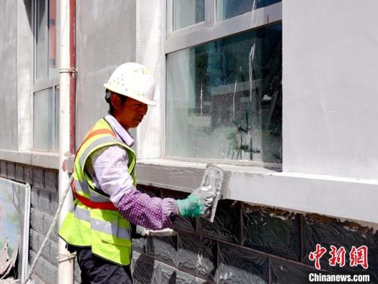 图为甘沟乡中心学校施工人员正在粉刷墙体。石军 摄 图为甘沟乡中心学校施工人员正在粉刷墙体。石军 摄