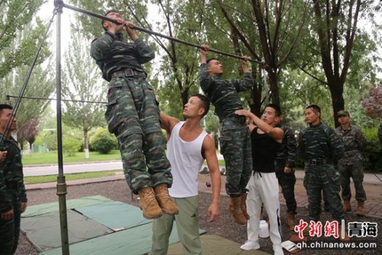 图为余乐斌教练团队成员正在给官兵进行单杠教学与纠错。 刘进峰摄