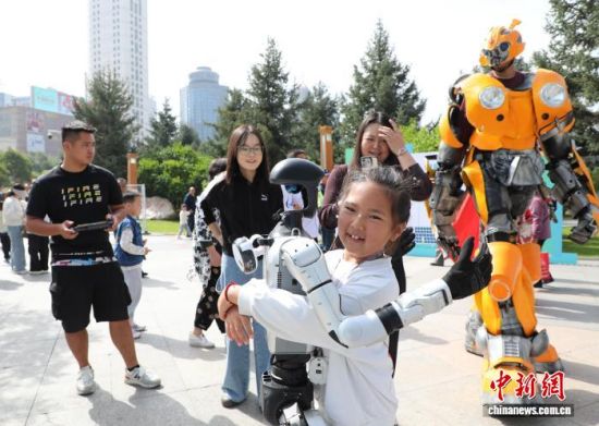图为活动现场，小朋友和机器人互动拥抱。马铭言摄