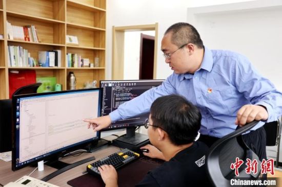 图为蔡海宁(右)指导同事进行编程。张添福 摄 图为蔡海宁(右)指导同事进行编程。张添福 摄