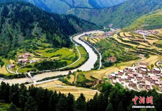 图为班前村与玛可河林场全景，村庄与原始森林错落呼应。尕藏扎西供图