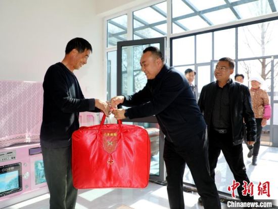 图为乡镇干部为入住村民恭贺乔迁之喜。马芳 摄 图为乡镇干部为入住村民恭贺乔迁之喜。马芳 摄